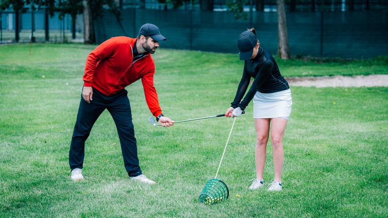 Golf instructor working with young woman on swing improvement