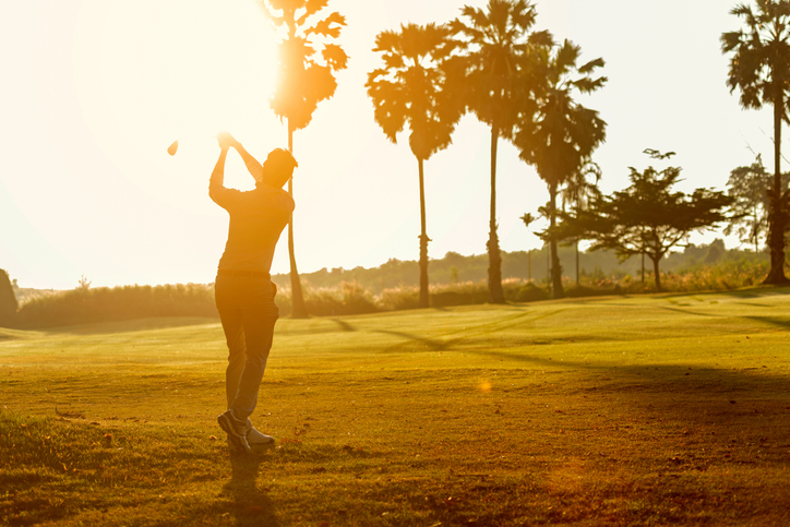 Silhouette Professional Golfer asian man swing and hitting golf ball practice at golf driving range and fairway in sunny morning day on multiethnic club golf. Lifestyle and Sport Concept