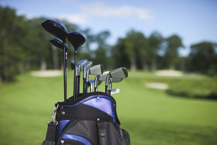 Golf bag and clubs against defocused green background