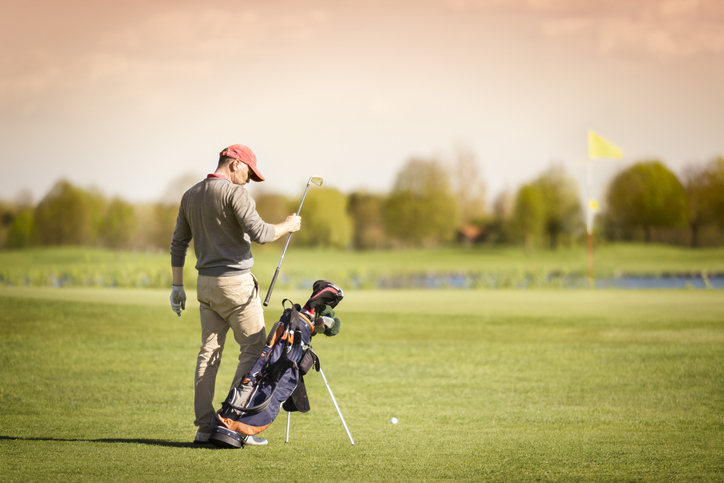 Golf player pulling out club on green.