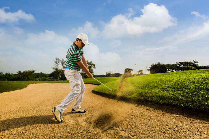 Golfer hitting the ball on the sand. Speeds Cause blurred by movement